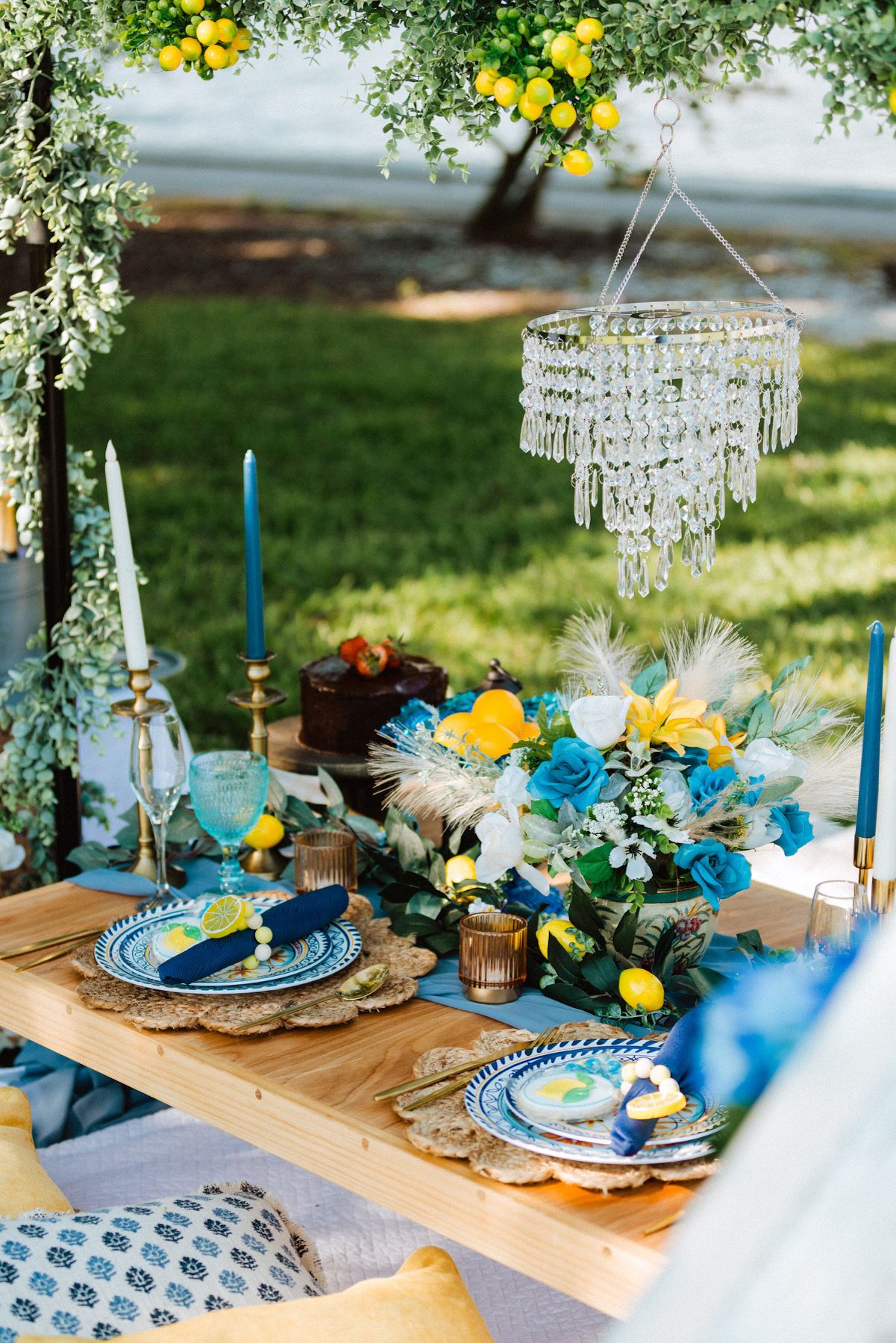 Mediterranean-inspired tablescape with lemons, blue accents, and a crystal chandelier
