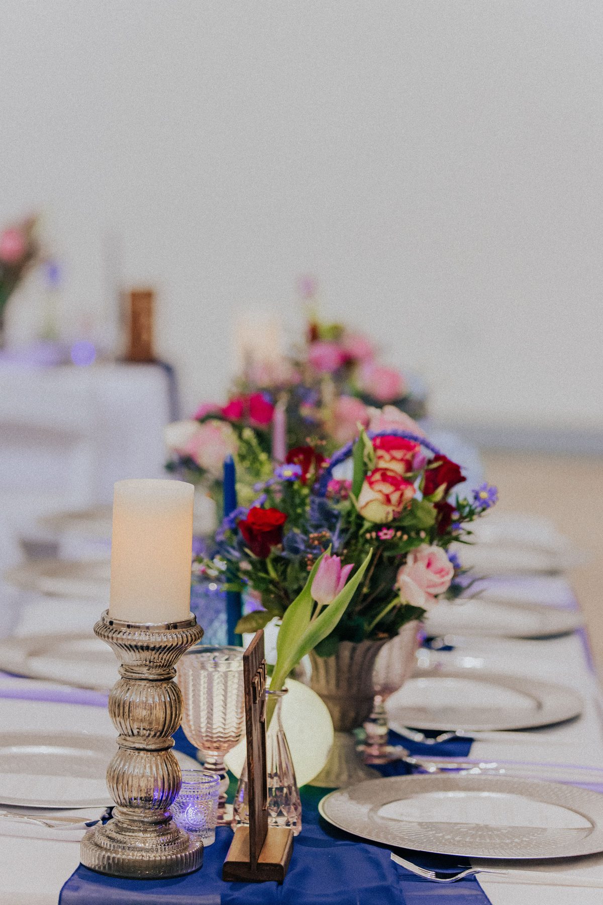 Reception table detail with jewel-tone florals and candles