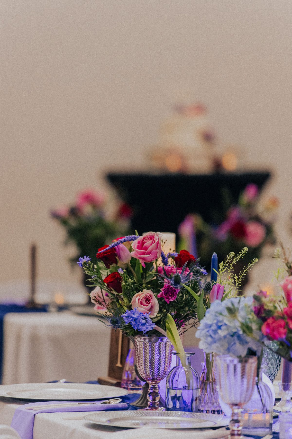 Pink, red, and blue floral centerpieces by candlelight