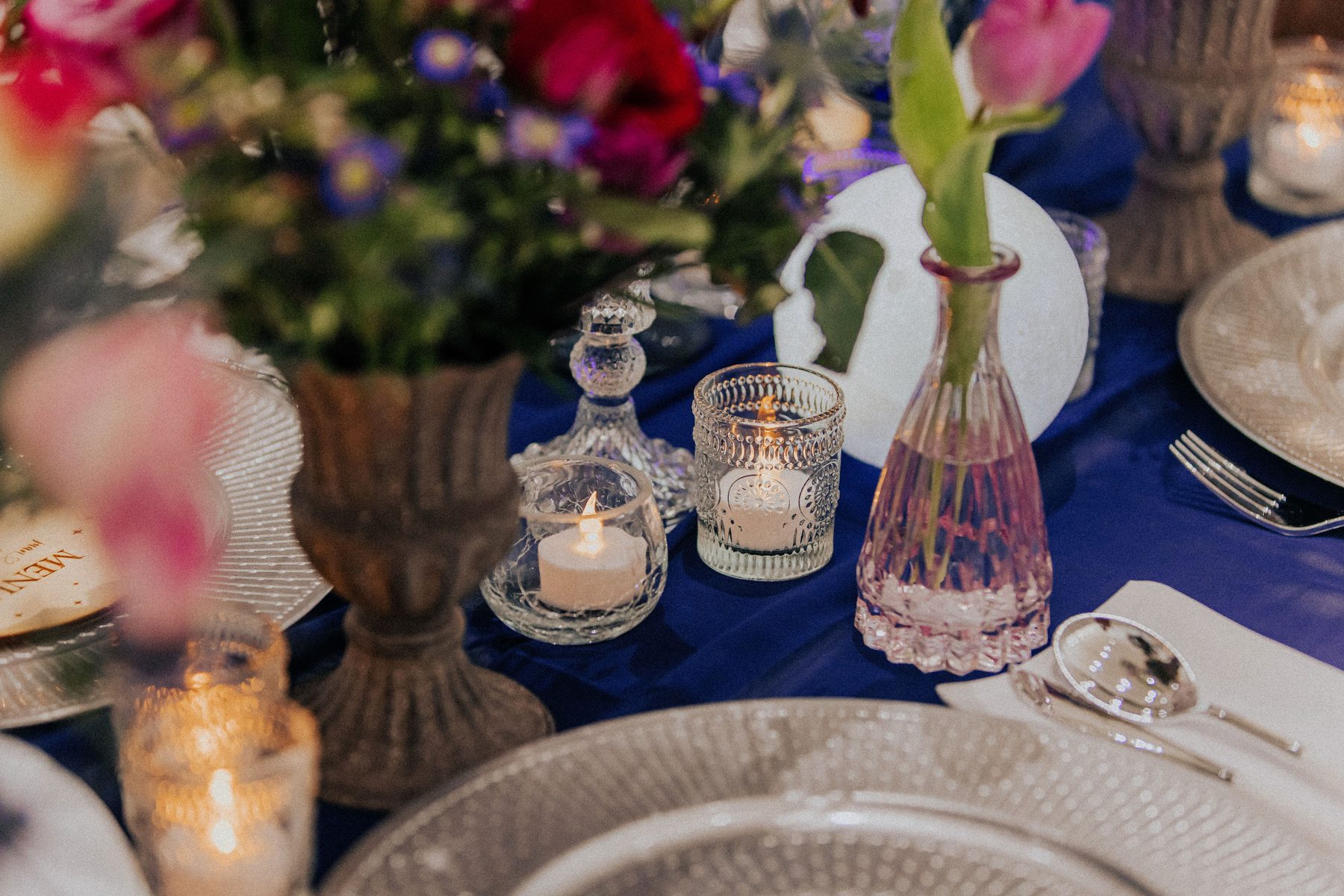 Candle and glassware table detail in jewel tones